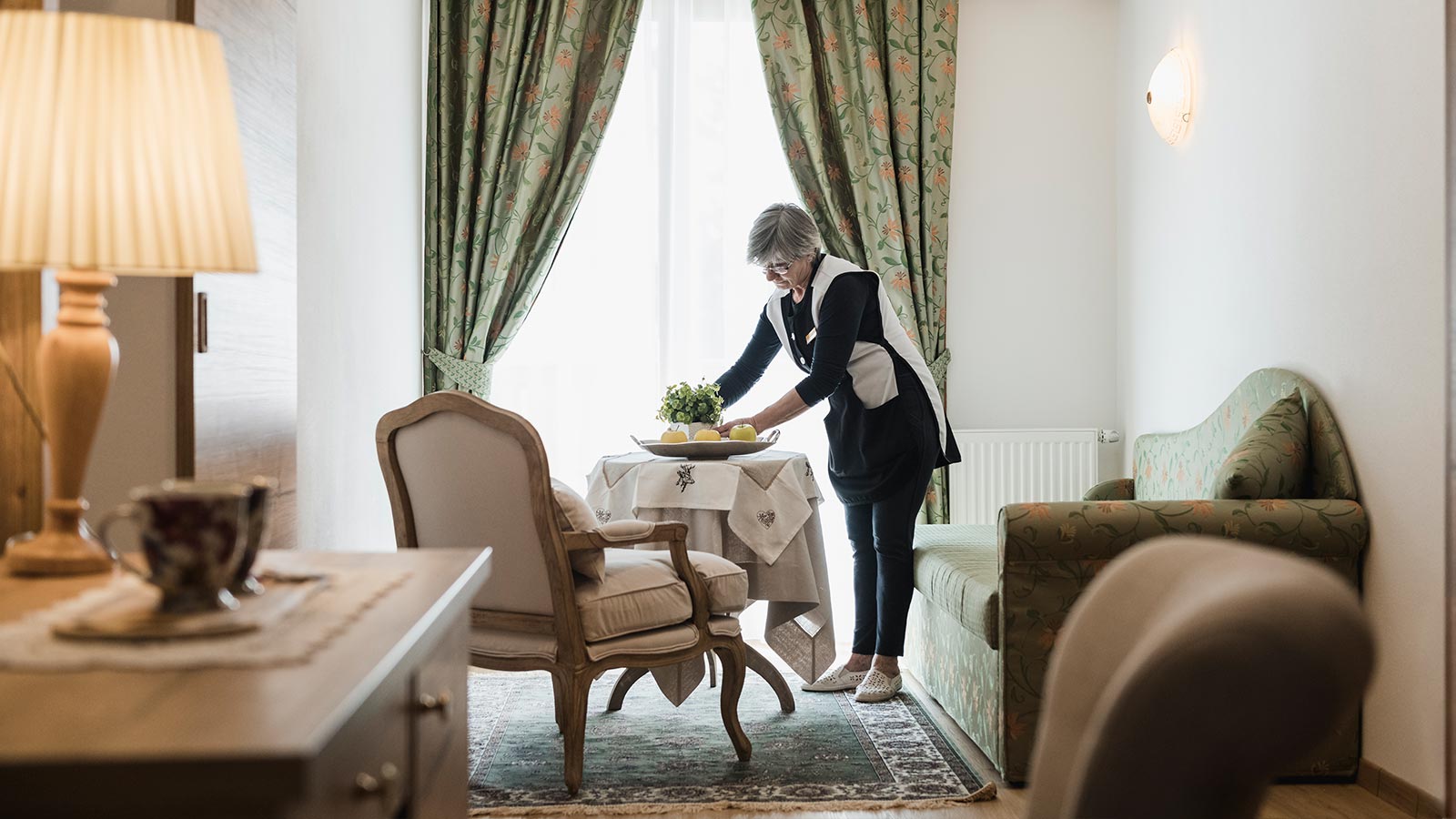 A waitress arranges a plant in one of the rooms of the Hotel Laguscei