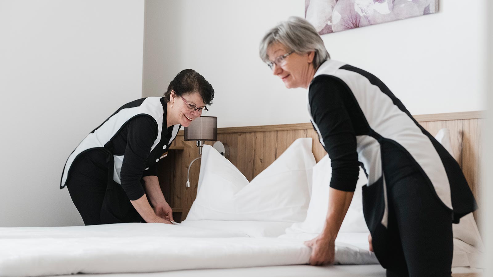 Two waitresses make the bed in one room